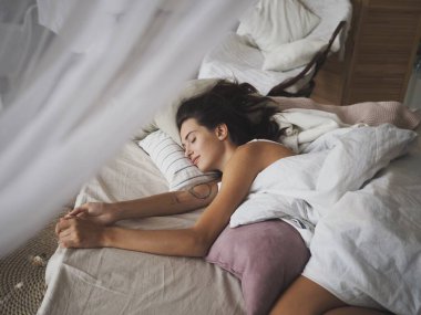 Evde yatakta uyuyan genç kadın.