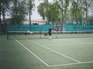 Genç bir kadın spor için stadyuma koşuyor, esniyor, su içiyor.