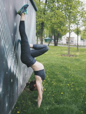 Genç bir kadın spor için stadyuma koşuyor, esniyor, su içiyor.