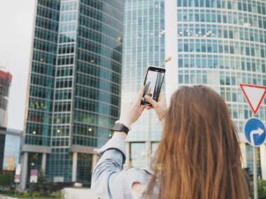 Genç bir kadın şehirde yürüyor ve evde fotoğraf çekiyor.