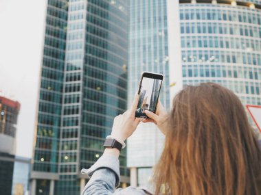 Genç bir kadın şehirde yürüyor ve evde fotoğraf çekiyor.