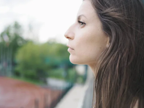 Genç bir kadın spor için stadyuma koşuyor, esniyor, su içiyor.