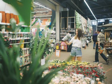 Çiçekçide bir kadın ev bitkilerini seçer.