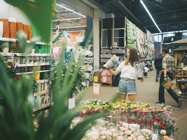 Çiçekçide bir kadın ev bitkilerini seçer.