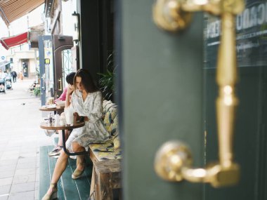Genç bir kadın yazın verandada bir kafede yemek yiyor.