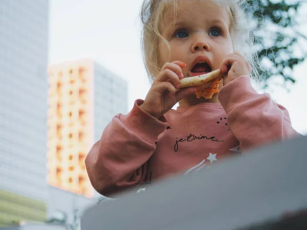 child eating takeaway pizza with dad on the street