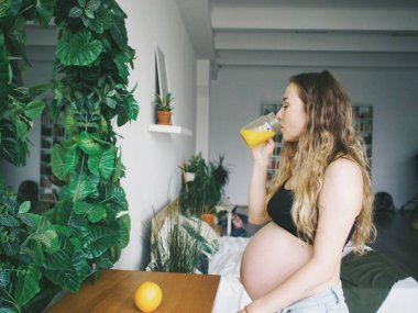 Hamile kadın taze sıkılmış portakal suyu ve hamile kadınlar için vitaminler içiyor.