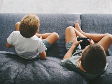 Çocuklar TV 'de bilgisayar oyunu joystick konsolu oynuyorlar