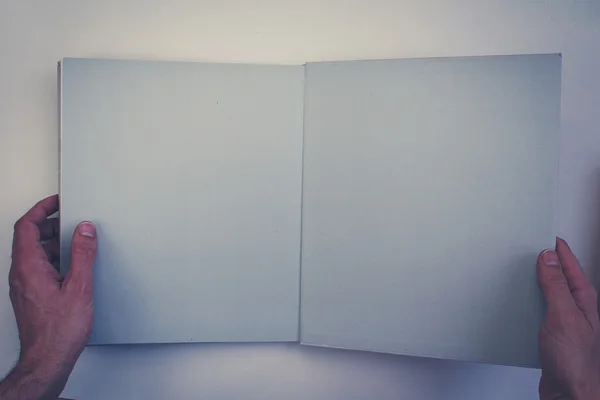 Hände halten aufgeschlagenes Buch mit leeren Seiten — Stockfoto