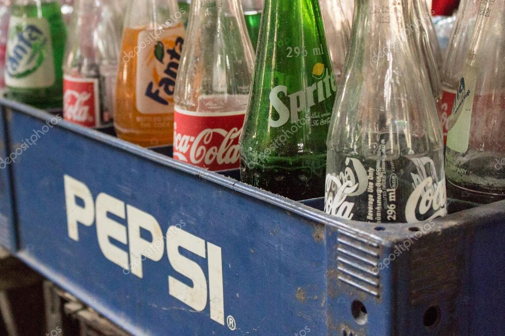 Phnom Penh, Cambodia- January 02, 2014. Coca-Cola bottles in  Pepsi in Pepsi container - vintage style. Symbolic representation of one of the greatest business rivalries of all time.