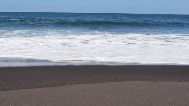 Чорний пляж, океанські хвилі і блакитне небо пісок, море і небо — стокове відео