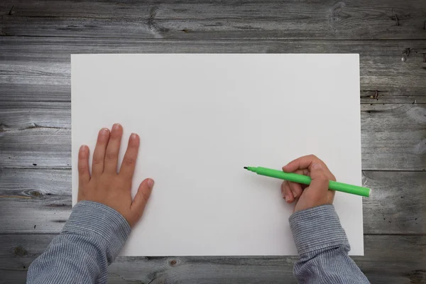 Дитина тримає ручку на чистому аркуші паперу. дитячі руки малюють на столі — стокове фото