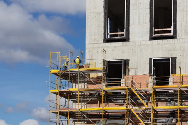 Trabajadores de la construcción en andamios - edificio fachada constructi —  Fotos de Stock