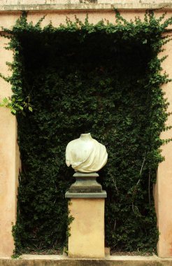 Arka planda yeşil bitkiler olan dekoratif heykel