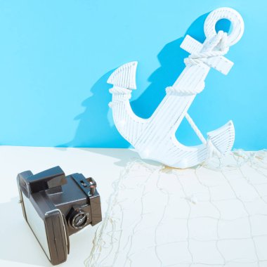 Eski kamera ve ahşap çapayla yapılmış yaz minimumu bir konsept. Mavi ve kum rengi arkaplanda.