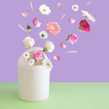 Çöp kutusundan çıkan çeşitli taze bahar çiçekleri, pastel mor arka plana karşıdır. Asgari doğa kavramı.