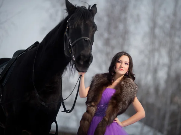 Vacker ung kvinna med en svart häst — Stockfoto