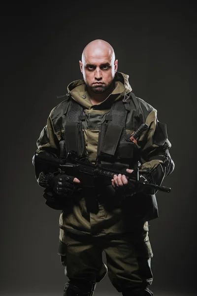 Soldado hombre mantenga ametralladora sobre un fondo oscuro — Foto de Stock