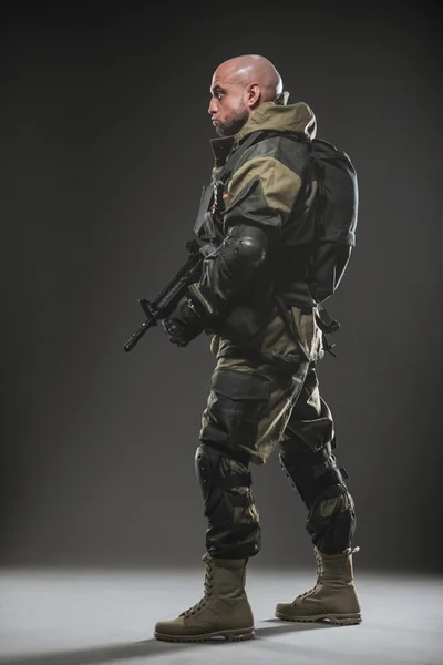 Żołnierz człowiek posiada karabin maszynowy na ciemnym tle — Zdjęcie stockowe