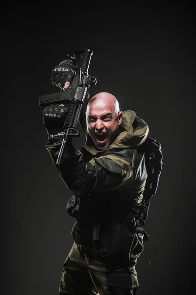 Soldado homem segurar metralhadora em um fundo escuro — Fotografia de Stock