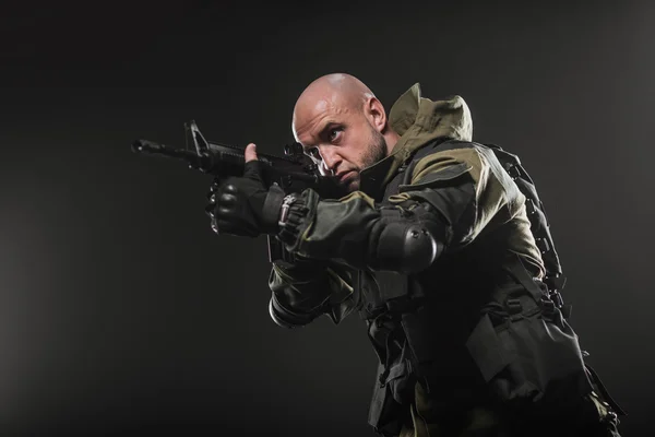 Солдат держит пулемет на темном фоне — стоковое фото