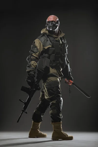 Katona az ember tartsa géppuska egy sötét háttér — Stock Fotó