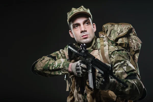 Soldado hombre mantenga ametralladora sobre un fondo oscuro — Foto de Stock