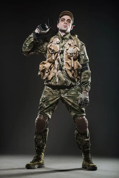 Soldado homem segurar metralhadora em um fundo escuro — Fotografia de Stock