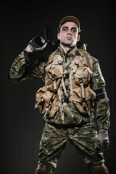 Żołnierz człowiek posiada karabin maszynowy na ciemnym tle — Zdjęcie stockowe