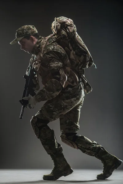 Katona az ember tartsa géppuska egy sötét háttér — Stock Fotó