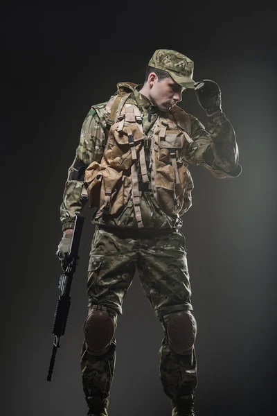 Soldado hombre mantenga ametralladora sobre un fondo oscuro — Foto de Stock