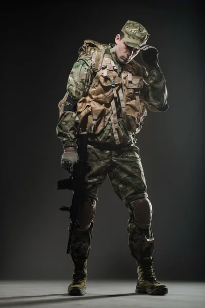 Soldado hombre mantenga ametralladora sobre un fondo oscuro — Foto de Stock