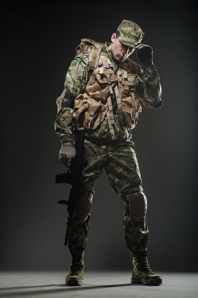Солдат держит пулемет на темном фоне
