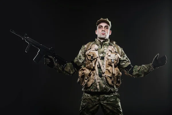 Voják muž drží kulomet na tmavém pozadí — Stock fotografie