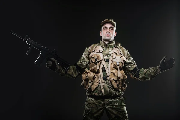 Soldado homem segurar metralhadora em um fundo escuro — Fotografia de Stock