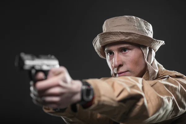 Soldado com uma arma aponta para fundo escuro — Fotografia de Stock