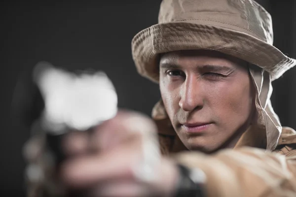 Солдат с пистолетом прицеливается на темном фоне — стоковое фото