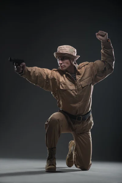 Soldat avec un pistolet vise sur fond sombre — Photo