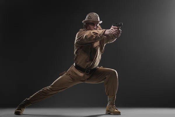 Soldato con una pistola prende di mira su sfondo scuro — Foto Stock