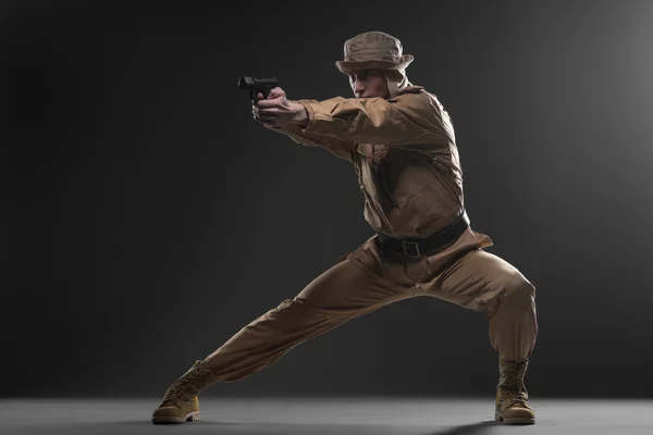 Soldier with a gun takes aim on dark background — Stock Photo, Image