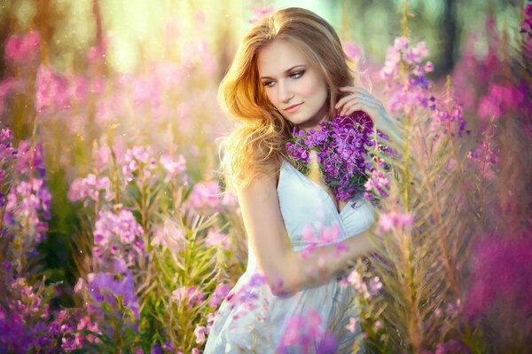 Art photo: young beautiful girl in the flowered field on sunset