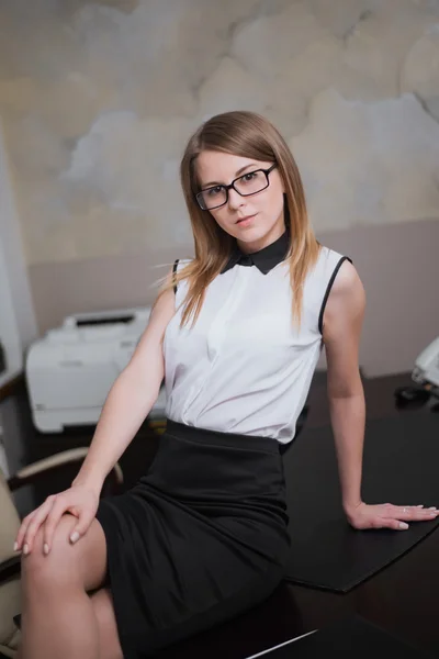 Sexy zakenvrouw zittend op de tafel in kantoor — Stockfoto