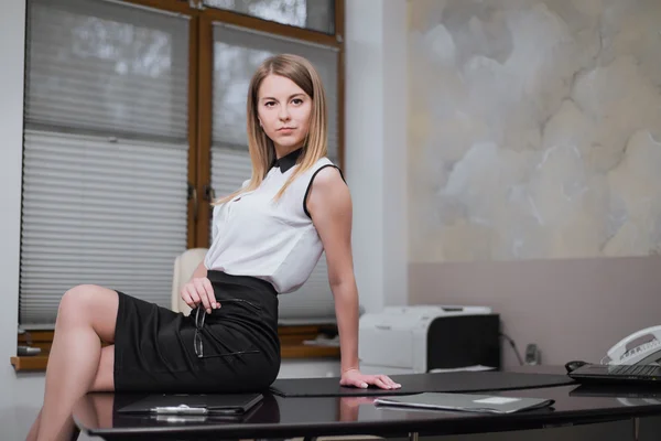 Sexy business woman sitting on the table in office — Stock Photo, Image