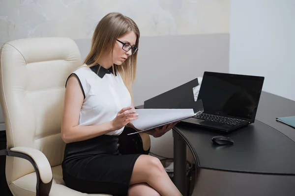 Sexy business woman is sitting at the desk in office — Stock Photo, Image