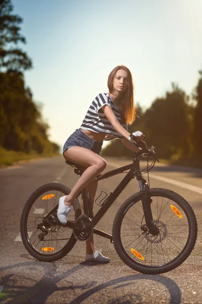 Menina em uma bicicleta ao pôr do sol — Fotografia de Stock