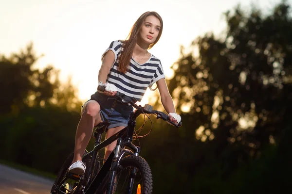 Chica en una bicicleta al atardecer — Foto de Stock