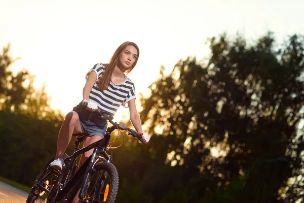 Mädchen auf einem Fahrrad bei Sonnenuntergang — Stockfoto