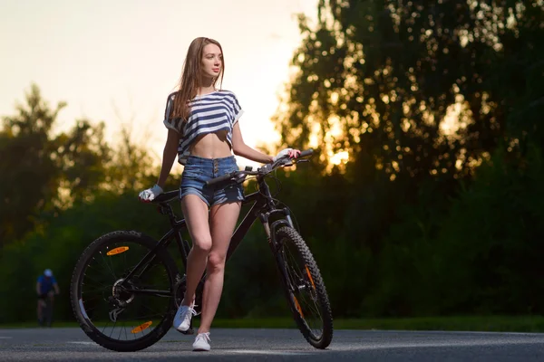 Menina em uma bicicleta ao pôr do sol — Fotografia de Stock