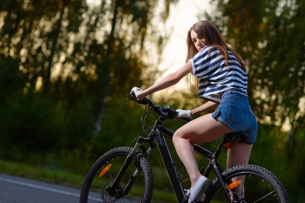 Chica en una bicicleta al atardecer — Foto de Stock