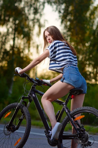 Chica en una bicicleta al atardecer — Foto de Stock